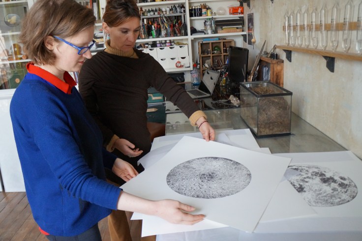 Anaïs Tondeur montre quelques reproductions de ses dessins de la Lune, à Marie Mirepois, dans son atelier de Montreuil.